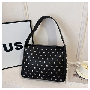 Close-up of black lychee texture leather shoulder bag with silver rivet studs
