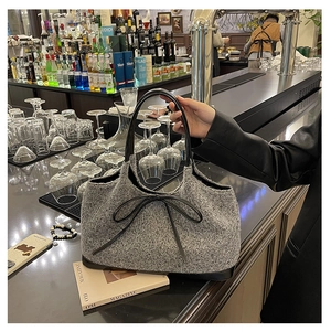 Grey plush handbag with black leather bow detail and sturdy handles for commute