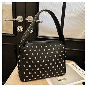 Detailed view of black lychee grain leather handbag with decorative silver metal rivets