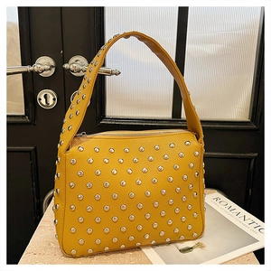 Close-up of yellow textured leather handbag with silver metallic rivets and sturdy handle