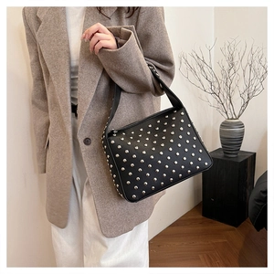 Detail of black leather shoulder bag with silver rivet studs and stylish strap