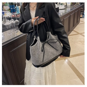 Detail view of the gray textured fabric tote bag with black leather trim and bow knot