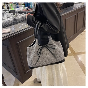 Detail of grey tweed tote bag with black bow decoration and reinforced leather handles