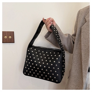 Detail of black punk style handbag featuring dense silver rivets on straps and PU leather