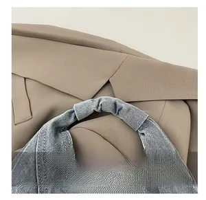 Détail de la bandoulière en denim froncé sur un sac hobo bleu délavé texturé