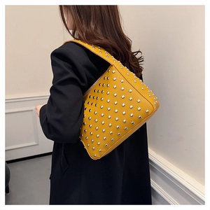 Detailed view of yellow lychee leather bag with silver rivets and metal studs