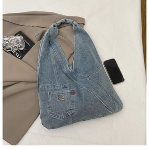 Détail d'un sac cabas en denim délavé bleu clair avec poche avant et poignée intégrée