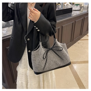 Detail of grey knitted tote bag featuring a black leather bow and textured wool finish