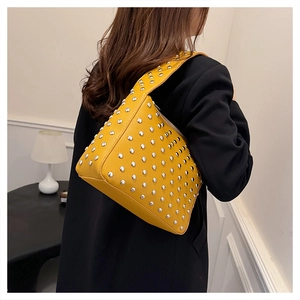 Detail of yellow pebbled leather shoulder bag with dense silver stud rivets and wide strap