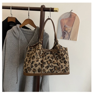 Close-up of leopard print plush tote bag with brown leather handles and decorative bow
