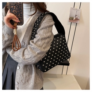 Detail of black studded shoulder bag in lychee texture leather worn by a model