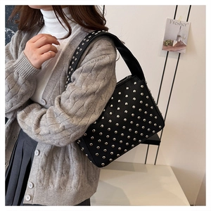 Close-up of black rivet-embellished hobo bag with silver studs and pebbled leather texture