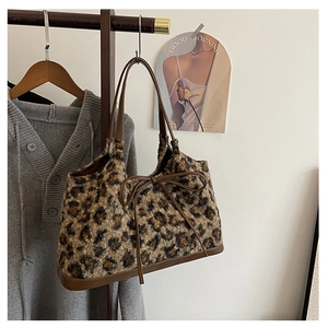 Detailed macro of leopard print plush tote bag with brown leather bow and strap details