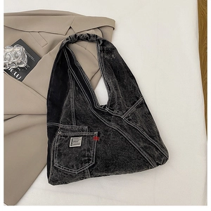 Détail du sac cabas en denim délavé avec coutures contrastées et petite poche