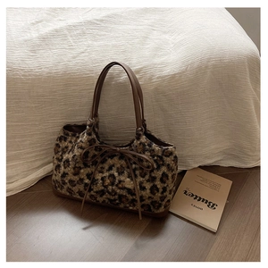 Close-up of leopard print plush tote bag showing soft texture and brown leather bow detail