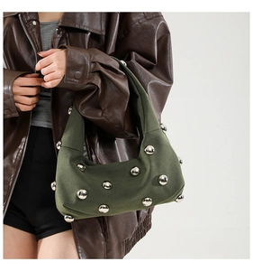 Detail of dark green hobo bag featuring large silver metal studs and a soft suede texture