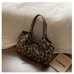 Close-up of plush leopard print tote bag with soft faux fur texture and leather bow detail