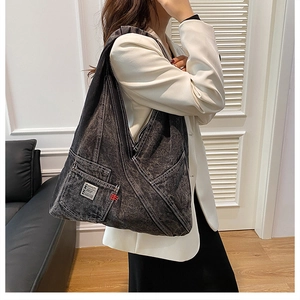 Vue macro d'un sac cabas en denim délavé gris foncé avec des surpiqûres contrastées blanches