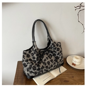 Detail of plush leopard print handbag with soft faux fur texture and black bow tie accent