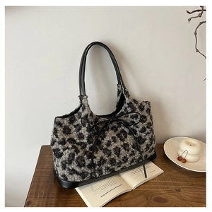 Close-up of leopard print plush tote bag with leather bow detail on wood table