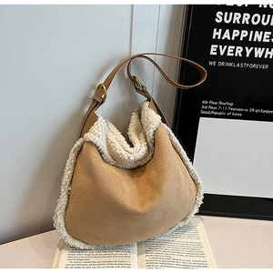 Détail du sac hobo en daim marron avec bordure en fausse fourrure blanche sur un livre
