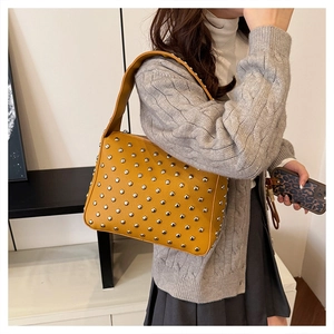 Detail of mustard yellow hobo bag with silver rivets and litchi grain leather texture