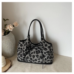 Detail of plush leopard print tote bag with black faux leather bow and handles