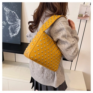 Detail view of bright yellow handbag with silver stud embellishments on a female model