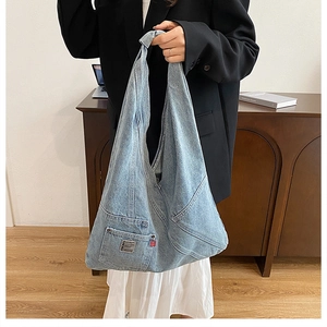 Détail du sac cabas en jean bleu délavé avec poche latérale et étiquette de marque rouge
