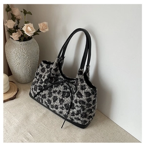 Close-up of leopard print plush tote bag with black leather handles and bow detail