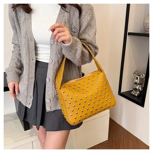 Detailed shot of yellow pebbled leather bag featuring dense silver stud embellishments