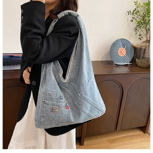 Détail du sac hobo en jean avec tissu patchwork délavé et poche avec logo de marque