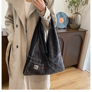 Sac fourre-tout en denim délavé gris noir avec surpiqûres porté par un mannequin