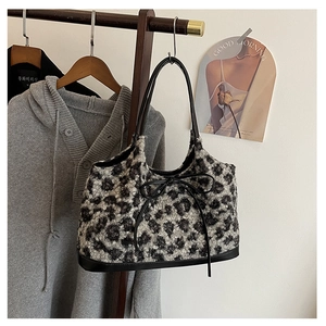 Detailed view of plush leopard print tote bag with black leather bow and handles