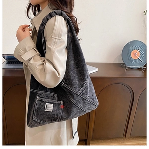 Détail du cabas en denim délavé avec surpiqûres blanches et poche utilitaire latérale
