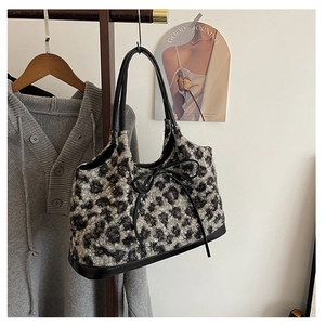 Detail of leopard print plush bag featuring black ribbon bow and faux fur texture