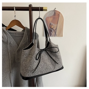 Detail of grey knit tote bag featuring large black leather bow and textured weave