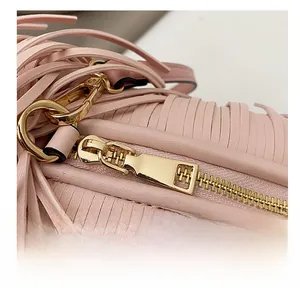 Detail of premium golden metal zipper and pink leather fringe on the stylish shoulder bag