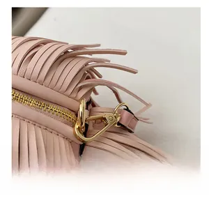 Close-up of premium gold metal hooks and fringe texture on a pink leather handbag