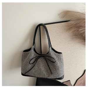 Detail of grey knitted wool fabric texture and black leather bow on large tote bag