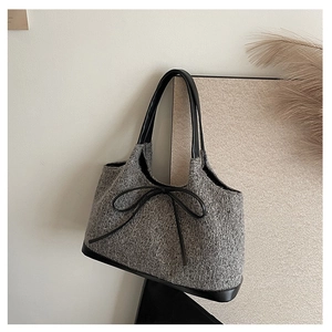 Detail of grey tweed tote bag with black leather trim and elegant bow accent