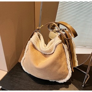Détail du sac hobo en daim marron avec garniture en peau de mouton blanche sur table en bois