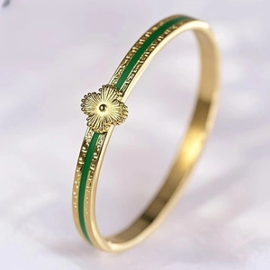 Detailed close-up of a gold-plated bangle featuring green enamel inlay and clover charm