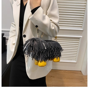 Macro view of unique black tassel dog-shaped bag with bright yellow paws and gold hardware