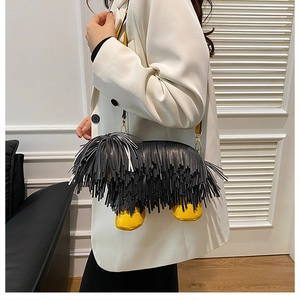 Detail of furry black puppy crossbody bag with yellow paw accents on a white blazer