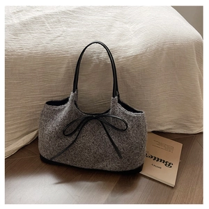 Detail of grey plush tote bag featuring black leather bow and slender shoulder straps
