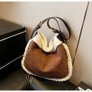 Détail de la bandoulière réglable et boucle dorée sur un sac cabas en daim marron