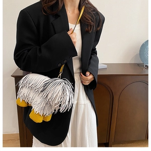 Quirky white tassel dog-shaped crossbody bag worn with a chic black blazer