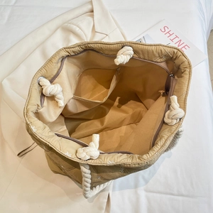 Quilted beige canvas tote bag with bow embroidery and rope strap in top view