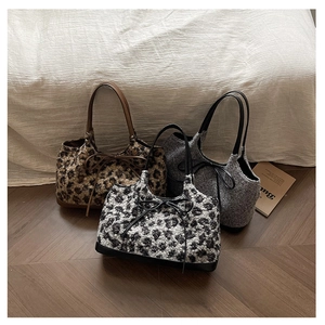 Three plush leopard print tote bags with decorative bows on cozy wooden floor